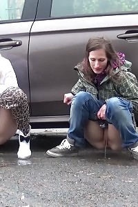 2 gfs piss behind a parked vehicle