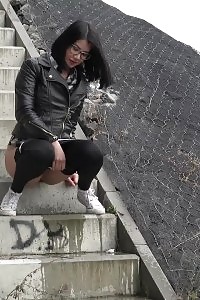 Kinky black haired doll in glasses pissing outside