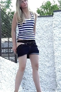 Sweetie pisses behind a white wall outside