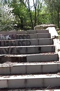 Black-haired doll pisses down some concrete steps
