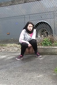 Brunette lady pisses by a public car park