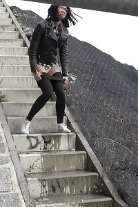 Kinky black haired doll in glasses pissing outside